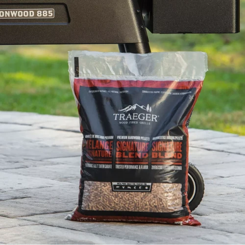Bag of Traeger Signature Blend wood pellets on a patio with a grill in the background, ready for grilling.
